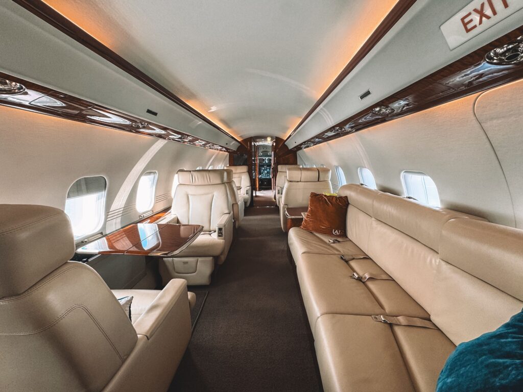 Luxury private jet cabin interior with cream leather seating and polished wood finishes